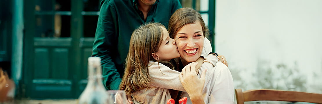 Girl kissing mother while celebrating birthday